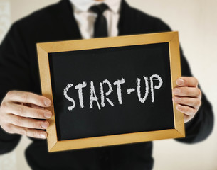 male businessman in a suit with tie holds in his hand a sign with the inscription START-UP