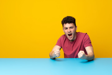 Young man with colorful wall and table frustrated by a bad situation