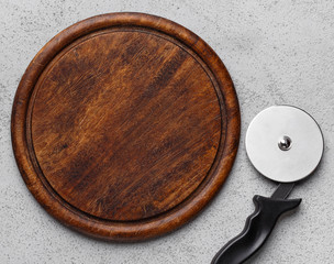 Pizza cutter and wooden cutting board, top view