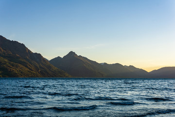 peaceful landscape during sunset with calm sky above the lake and mountain range