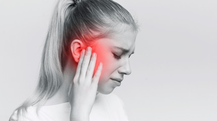 Woman having ear pain, touching her painful head