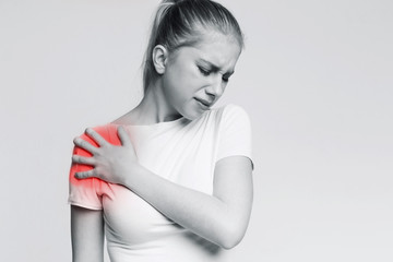 Young woman suffering from pain in shoulder