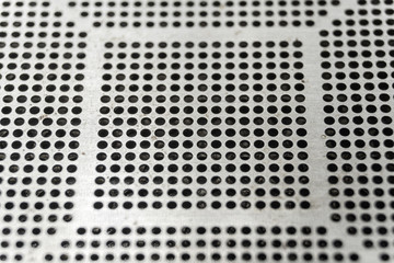 Close-up of used laser CNC high precision small pitch cut stencil for BGA chip reballing for electronics industry in partial focus on black background with flux residues