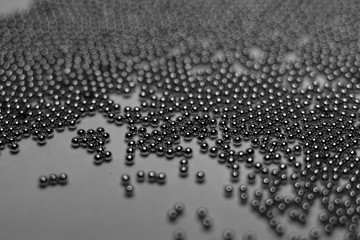 Close-up of industrial electronics assembly manufacturing materials RoHS 0.6mm round BGA soldering balls in partial focus randomly scattered on a gray background