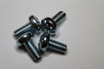 Close-up macro of four counter-clockwise arranged M3x6mm screws on white background 