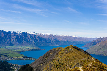 Fototapeta premium peaceful landscape during sunny day above the lake, valley and mountain range, footpath leading into the valley
