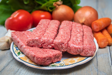 Minced meat for Kebab ready for barbeque. Traditional middle eastern and mediterranean eat. With fresh organic vegetable in the background.