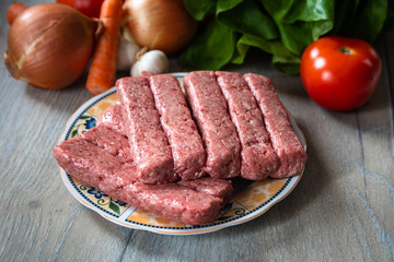 Minced meat for Kebab ready for barbeque. Traditional middle eastern and mediterranean eat. With fresh organic vegetable in the background.