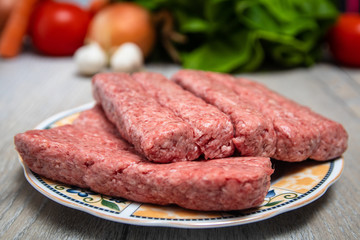 Minced meat for Kebab ready for barbeque. Traditional middle eastern and mediterranean eat. With fresh organic vegetable in the background.