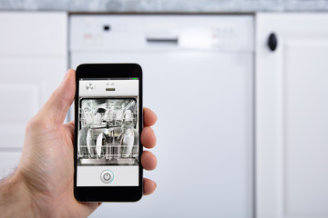 Person Operating Dishwasher With Smartphone