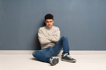 Young man sitting on the floor feeling upset