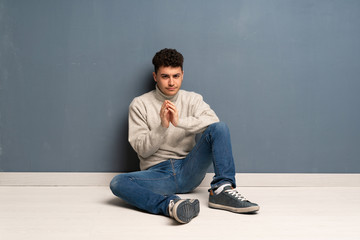 Young man sitting on the floor scheming something