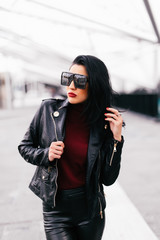 Fototapeta premium Fashion portrait woman in sunglasses outdoor. Young smiling woman wearing a rock black style having fun in city. Street fashion.