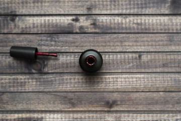 black bottle of red nail polish on wooden background. view from above. flatlay