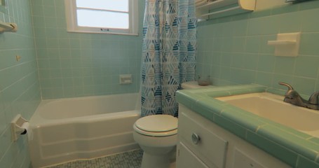Slider shot of old dated 1950s bathroom interior with green tile.