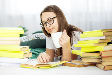 A girl is reading a book with glasses. Teenager drinks coffee. Concept of education, hobby and study and world book day