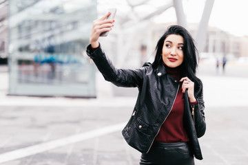 Young girl take selfie from hands with phone on autumn city street. Urban life concept.