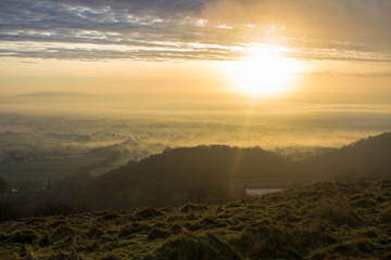 Sunrise above misty worcestershire seen from herefordshire beacon, malvern hills