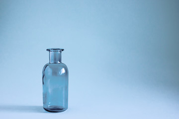 Glass blue bottle on a blue background.  Copy space