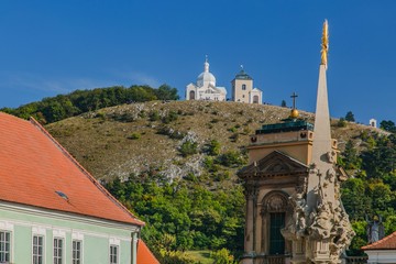 Fototapeta na wymiar A hill with Way of the Cross in South Moravia, Czech Republic, close to Mikulov town, called Holly Hill with Saint Sebastians Chapel and a bell tower, sunny day, blue sky, golden cross