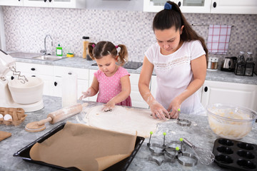 Mother And Daughter Making Cookies With Molds