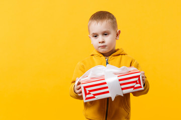 Naklejka premium Little kid boy 3-4 years old wearing yellow clothes hold gift box isolated on orange wall background, children studio portrait. People sincere emotions, childhood lifestyle concept. Mock up copy space