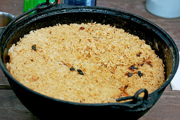 Traditional national food. Delicious, fresh, Uzbek pilaf in a metal cauldron.