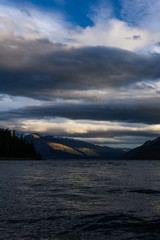 calm landscape during sunset with dramatic sky over lake and mountain range