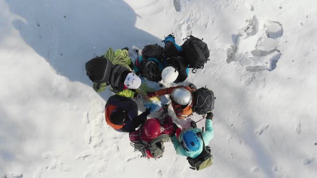 a group of climbers with backpacks and helmets confer looking at the map and checking the compass and also showing the side which will continue the route