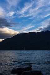 calm landscape during sunset with dramatic sky over lake and dark mountain