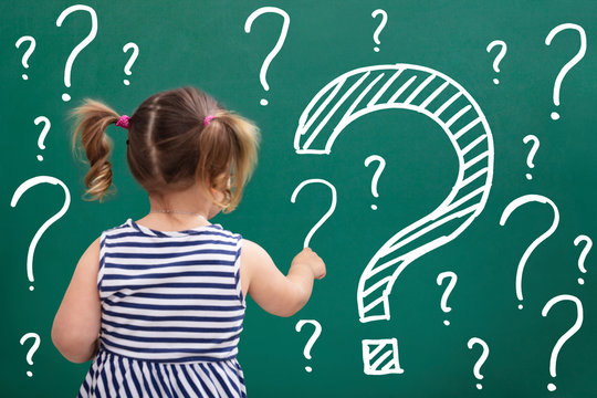 Little Girl Writing Question Marks On Chalkboard
