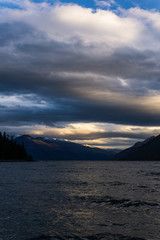 dramatic sky during dark sunset over mountain range, lake in the foreground
