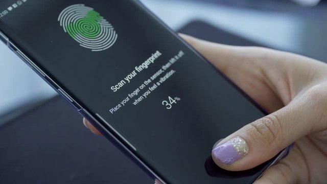 JAKARTA, Indonesia - March 14, 2019: Female finger scanning fingerprint on the sensor screen to secure the smartphone. Shot in 4k resolution