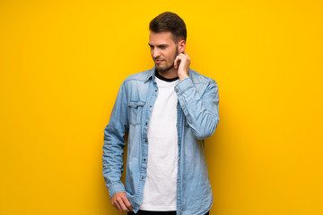 Handsome man over yellow wall having doubts