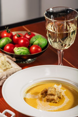 Pumpkin cream soup with croutons, baked chickpeas, sesame, parsley on a brown wooden background. Baked chickpeas with spices. Useful dietary snacks. Served with white wine and cheese