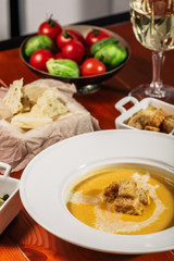 Pumpkin cream soup with croutons, baked chickpeas, sesame, parsley on a brown wooden background. Baked chickpeas with spices. Useful dietary snacks. Served with white wine and cheese