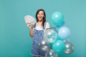 Excited young woman hold fan of money in dollar banknotes cash money celebrating with colorful air...