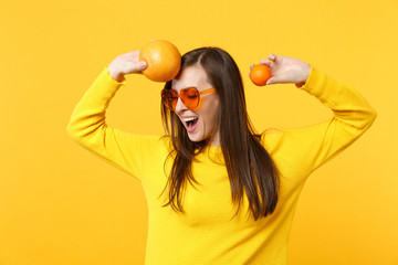 Cheerful young woman in heart glasses keeping eyes closed hold fresh ripe mandarin orange fruit...
