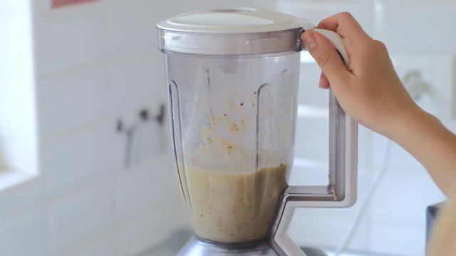 Making fruit smoothies, women's hands with a blender. Healthy diet at home in the kitchen