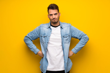 Handsome man over yellow wall angry