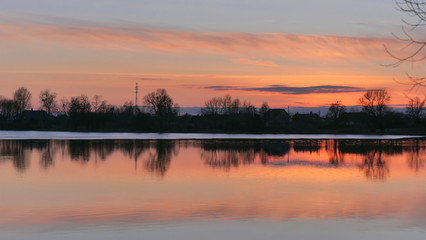 red sunset over the water of a village lake