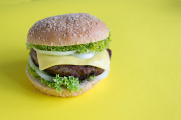 homemade hamburger with beef, cheese and salad on yellow background