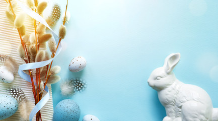 Easter greeting card with colorful easter eggs and sprin flowersl on blue table. Top view with space for your greetings - Image © Konstiantyn