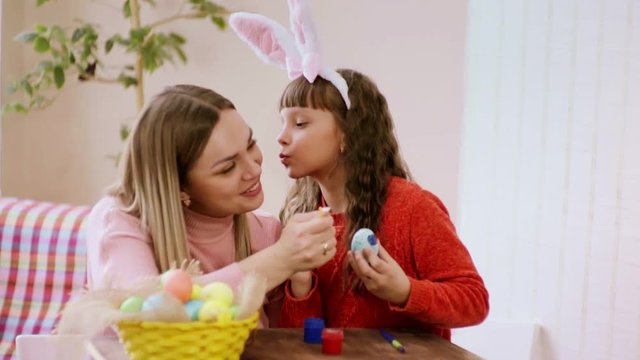 daughter kisses her mother on the cheek, during preparation for Easter.