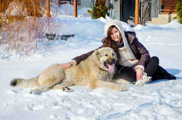 Beautiful Smiling Woman Playing with her Caucasian Shepherd Dog Outdoor in the  Winter.Owner and Dog Happy Together 