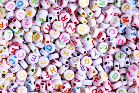 White beads with multicolored English letters close-up. - Powered by Adobe