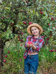 Portrait of a cute girl in a farm garden with a red apple.