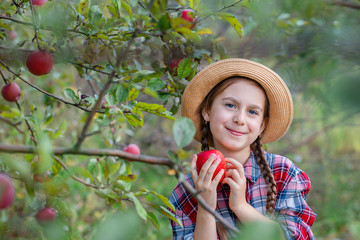 Portrait of a cute girl in a farm garden with a red apple.