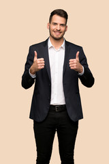 Handsome business man with thumbs up because something good has happened over ocher background