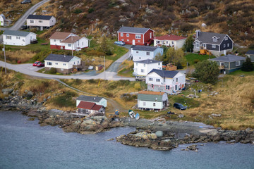 Fototapeta na wymiar Aerial view of a small town on a rocky Atlantic Ocean Coast during a cloudy day. Taken in St. Anthony, Newfoundland, Canada.
